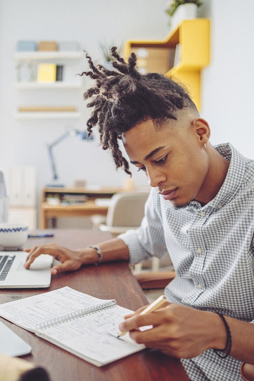 &eacute;tudiant prenant des notes &agrave; son bureau